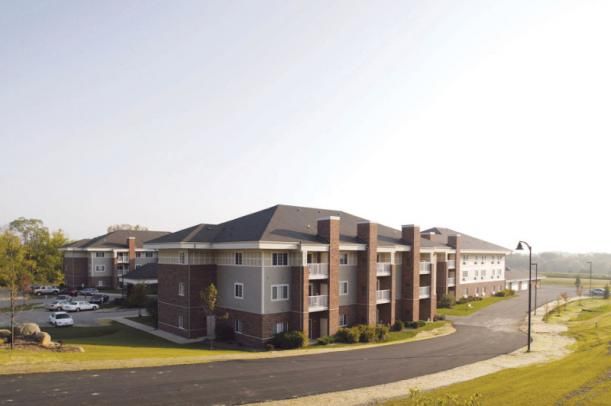 A modern suburban apartment building with multiple stories and a brick facade.