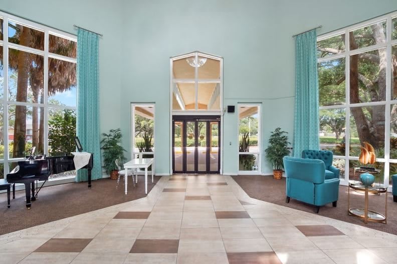 Spacious lobby area with large windows, seating, and decorative plants.