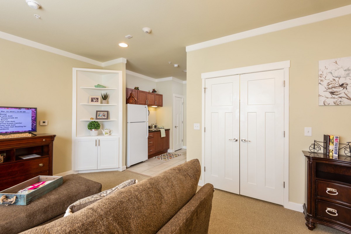Cozy living room with an open view of the kitchen featuring wooden cabinets and white appliances.