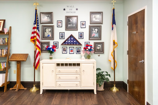 A serene memorial display featuring flags and framed photographs, honoring service members.