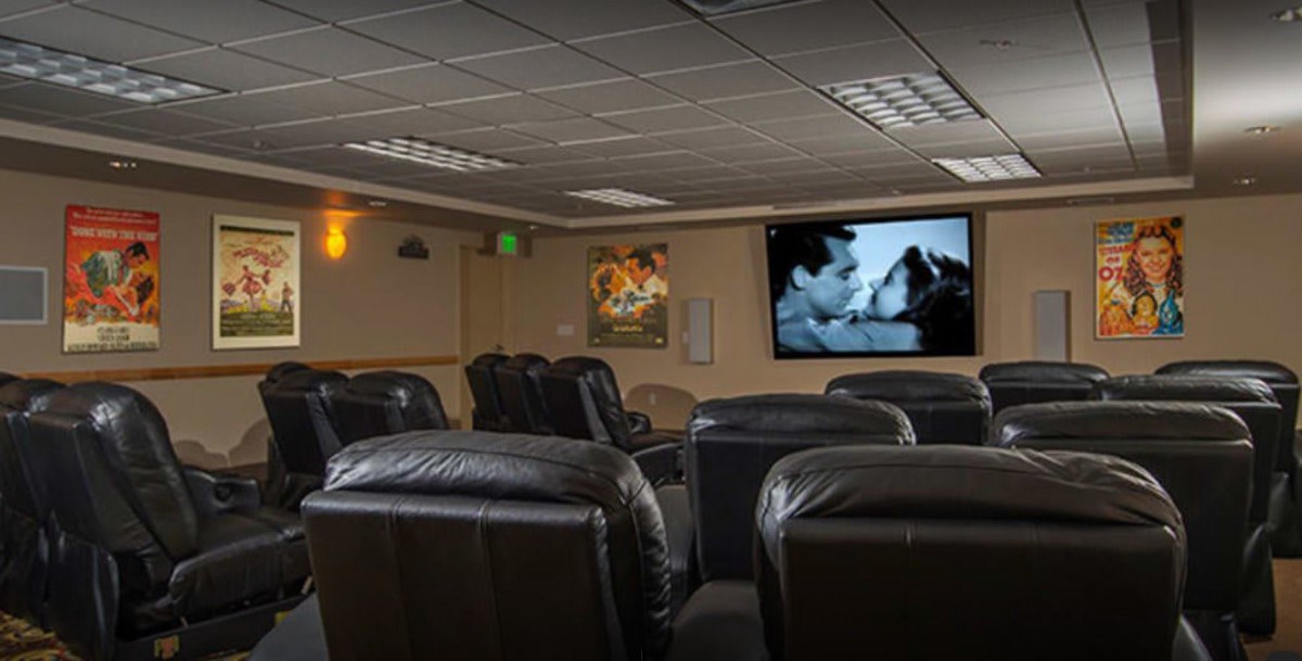 A cozy home theater with leather seating and a large projector screen displaying a black-and-white film.