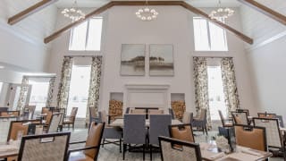 A modern dining room with high ceilings, chandeliers, and large windows.