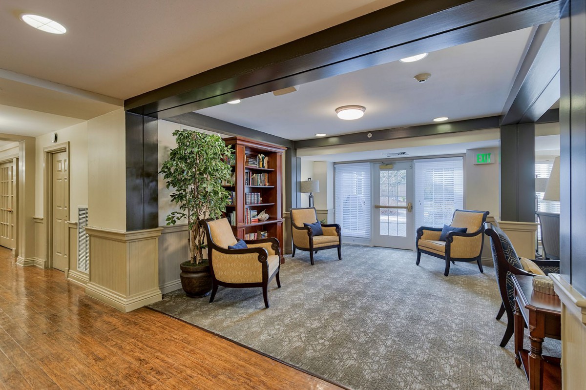 A cozy lobby seating area with comfortable chairs, bookshelves, and natural lighting.