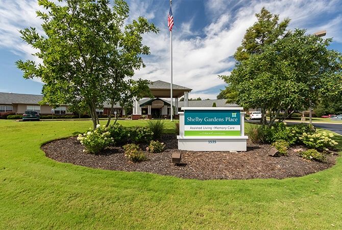 A hotel entrance with a prominent sign and well-maintained landscaping.