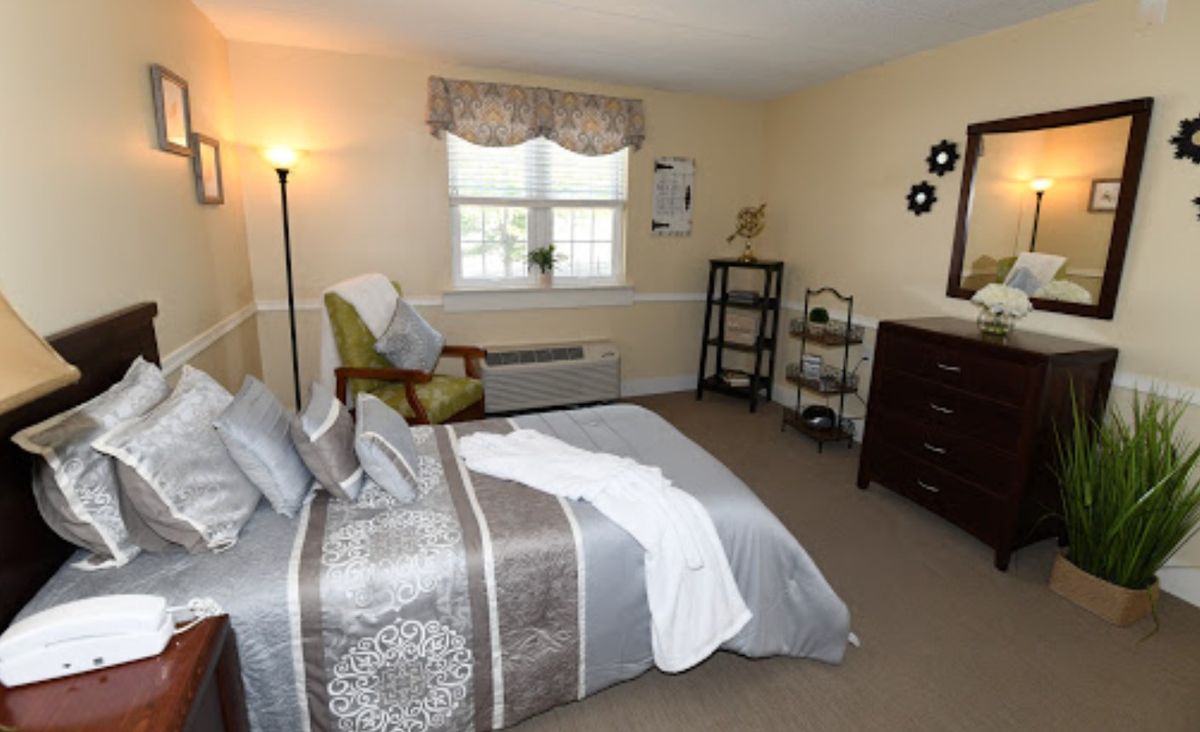 A cozy bedroom with a neatly made bed, stylish decor, and ample natural light.