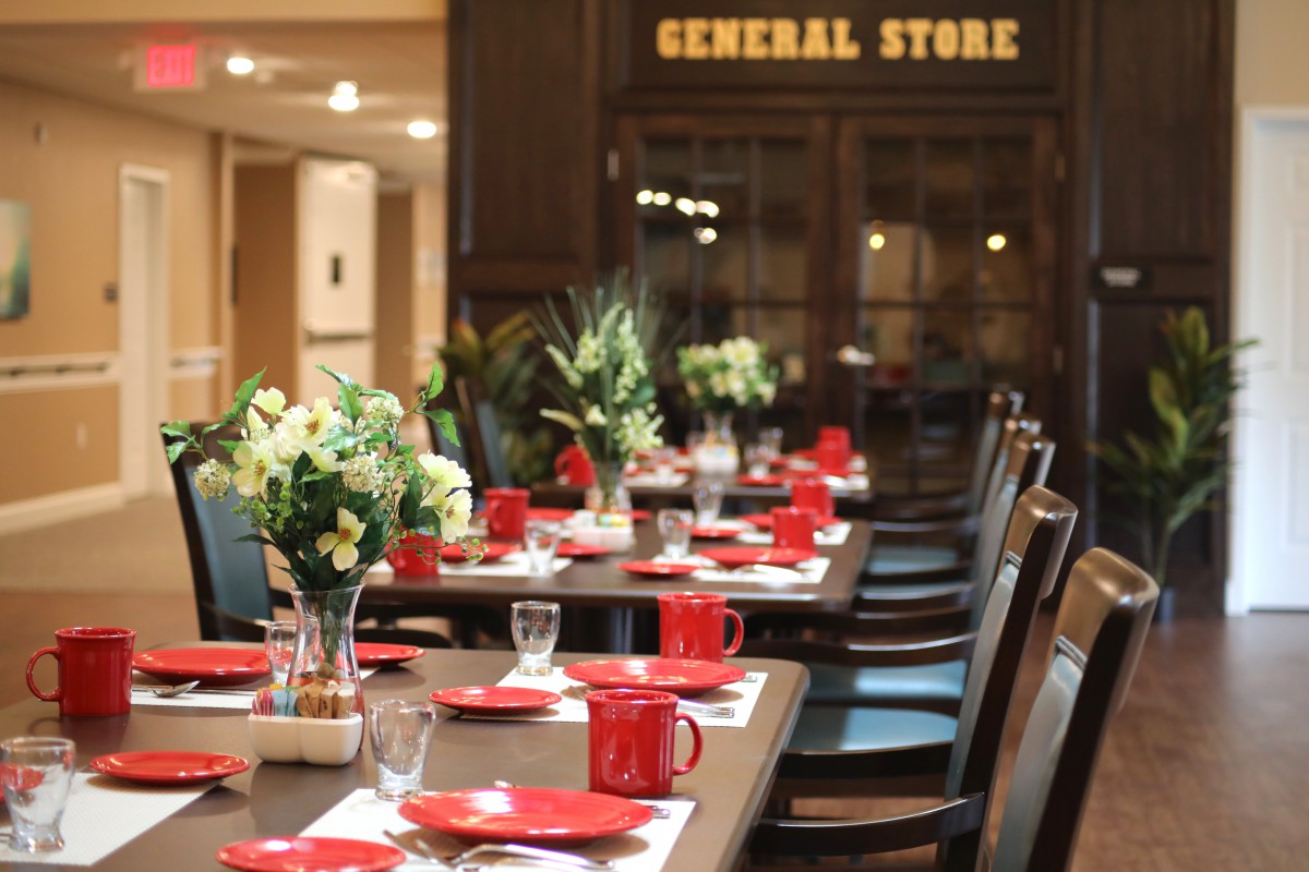 A beautifully set dining table with red crockery and flowers in a restaurant setting.