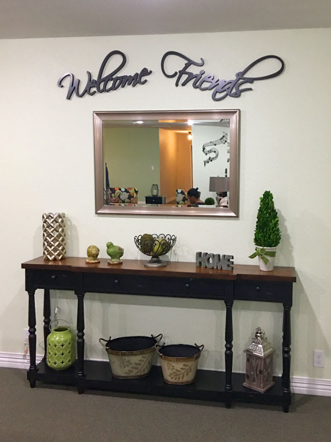 A warmly decorated entryway with a console table, mirror, and 'Welcome Friends' sign.