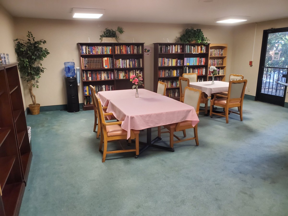 A cozy reading room with bookshelves, tables, and chairs, offering a welcoming space for relaxation.