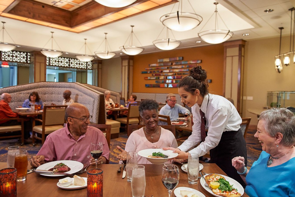 A waitress serves food to a group of people dining at a restaurant.