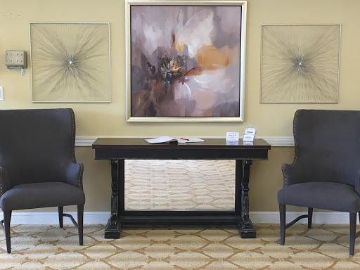 A stylish interior setup featuring two chairs flanking a console table with abstract art on the wall.
