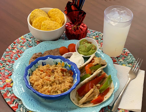 A vibrant Mexican meal featuring tacos, rice, guacamole, and a refreshing drink.