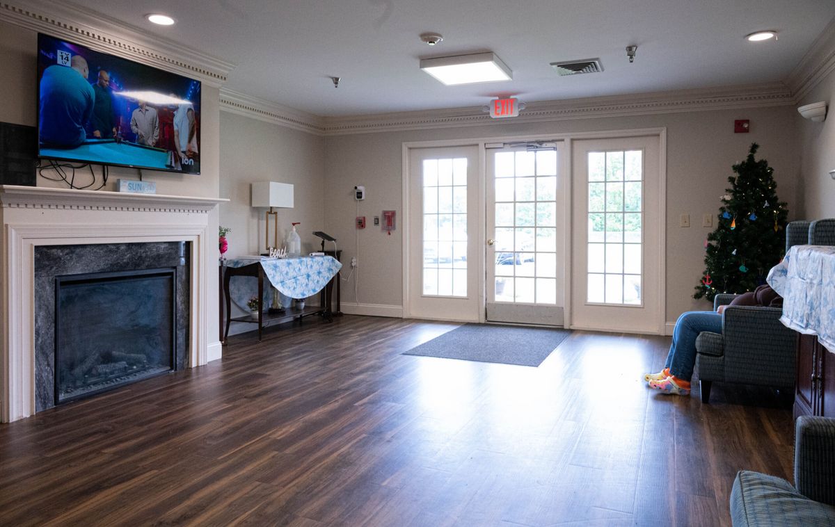 A cozy living room with a fireplace, television, and large windows.