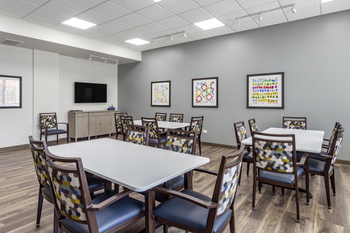 A modern meeting room with tables, chairs, and artwork on the walls.