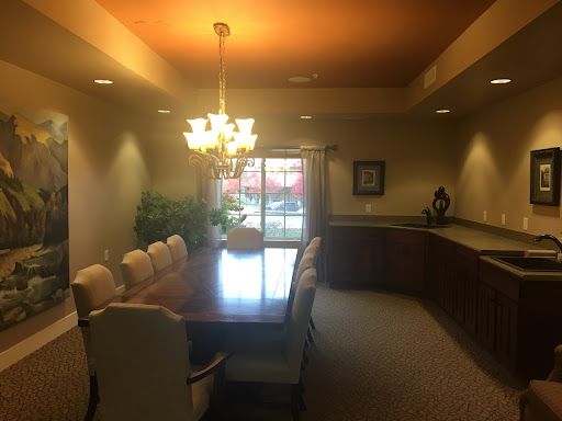 A spacious dining room featuring a large wooden table surrounded by elegant chairs, illuminated by a chandelier.