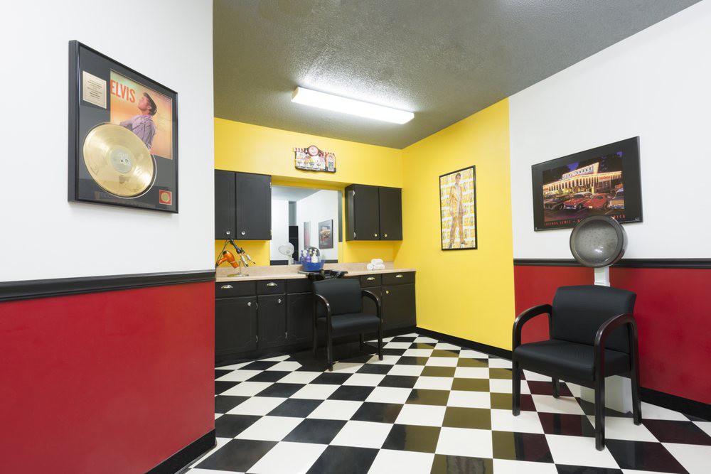 A brightly decorated waiting room with yellow and red walls, featuring a black and white checkered floor and black furniture.