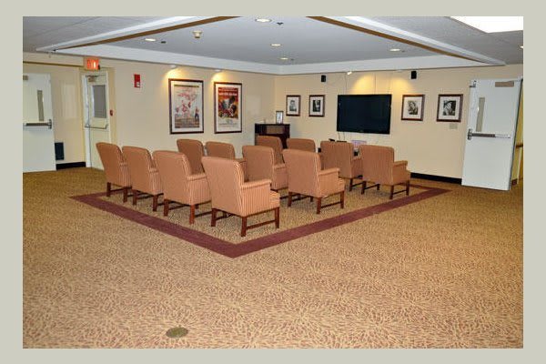 A conference room with arranged seating facing a television screen and framed pictures on the walls.