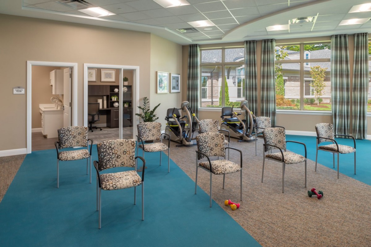 A well-lit exercise room with chairs and fitness equipment.