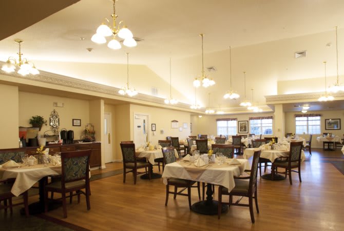 An empty dining room with neatly set tables and warm ambient lighting.