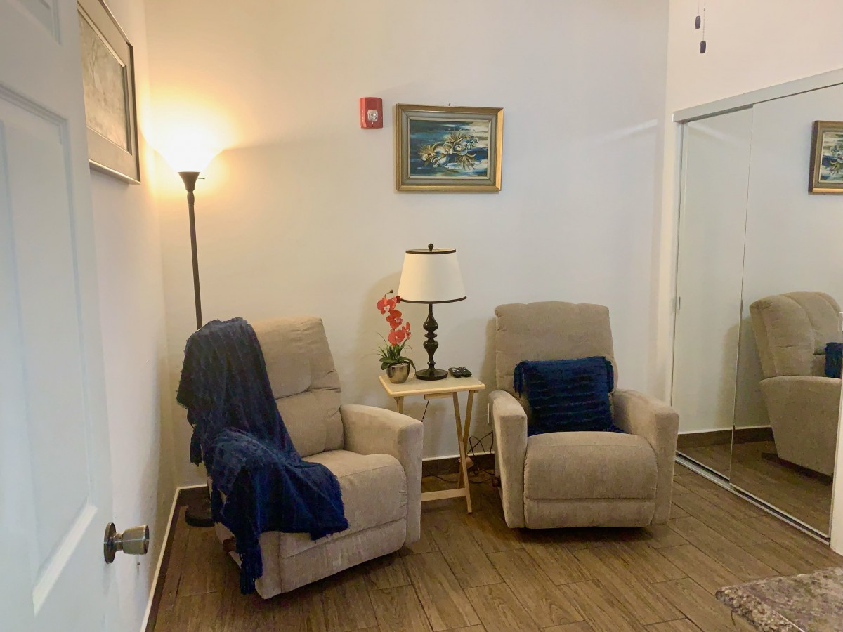 A cozy living room corner with two recliner chairs, a floor lamp, and decorative elements.