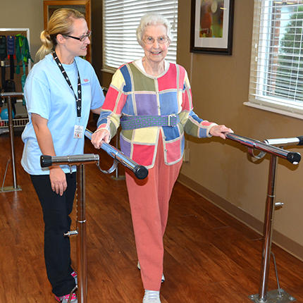An elderly woman receives assistance during a physical therapy session, focusing on regaining mobility and strength.