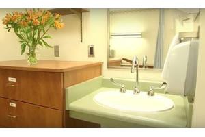 A clean and modern bathroom sink area with a mirror and flowers on the countertop.