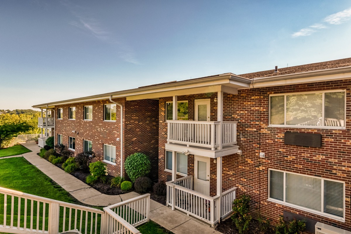 A brick apartment building with balconies and well-maintained landscaping.