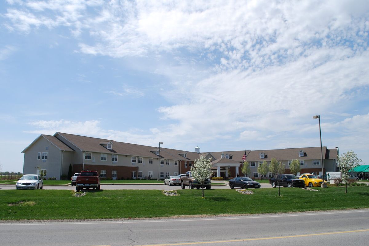 A large building with a parking lot in front, set against a cloudy sky.