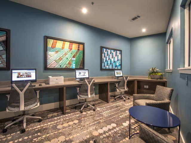 A modern office workspace with computers, artwork, and comfortable seating.