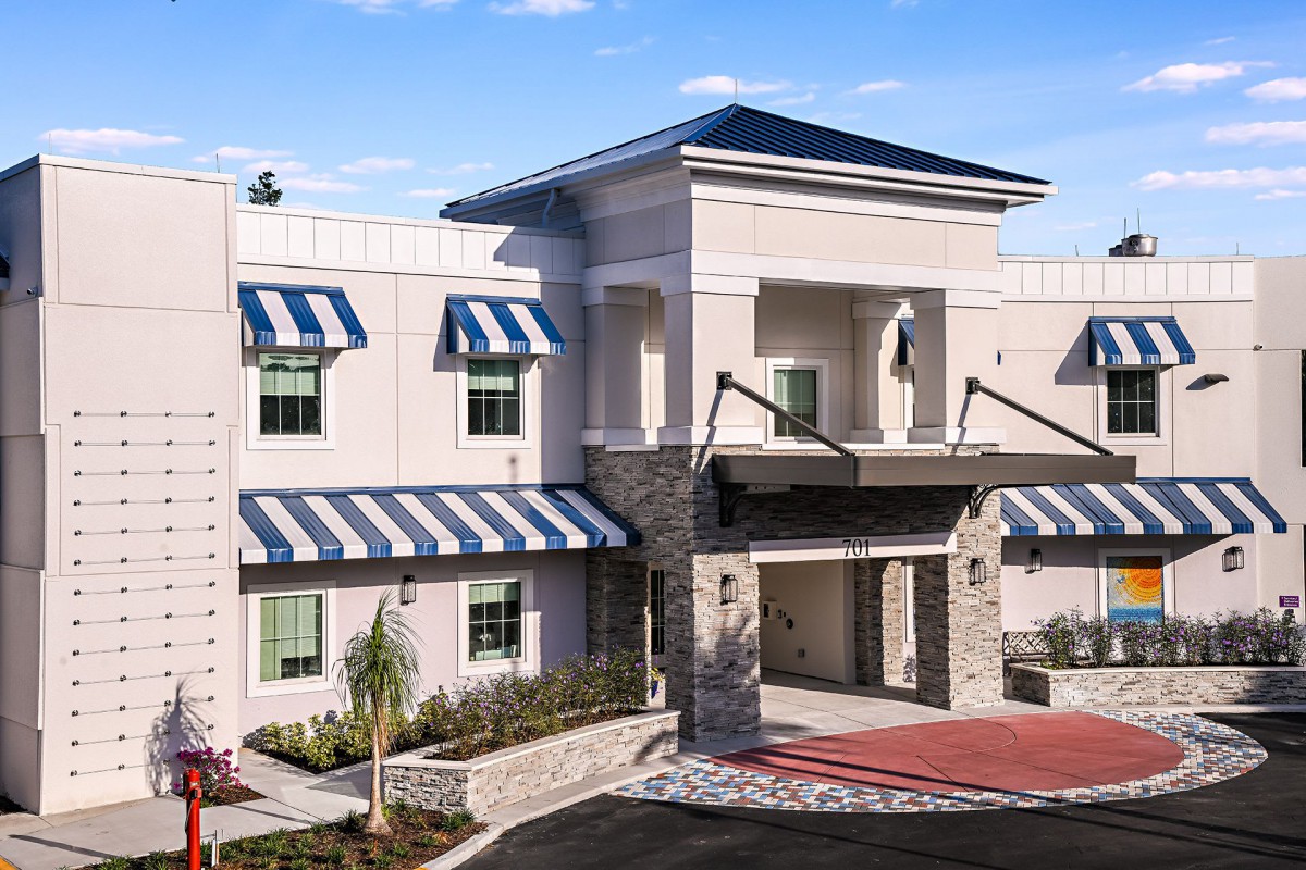 A modern building with striped awnings and a prominent entrance under a clear sky.