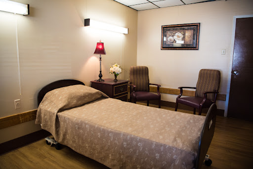 A cozy hospital room featuring a bed, chairs, and decorative elements.