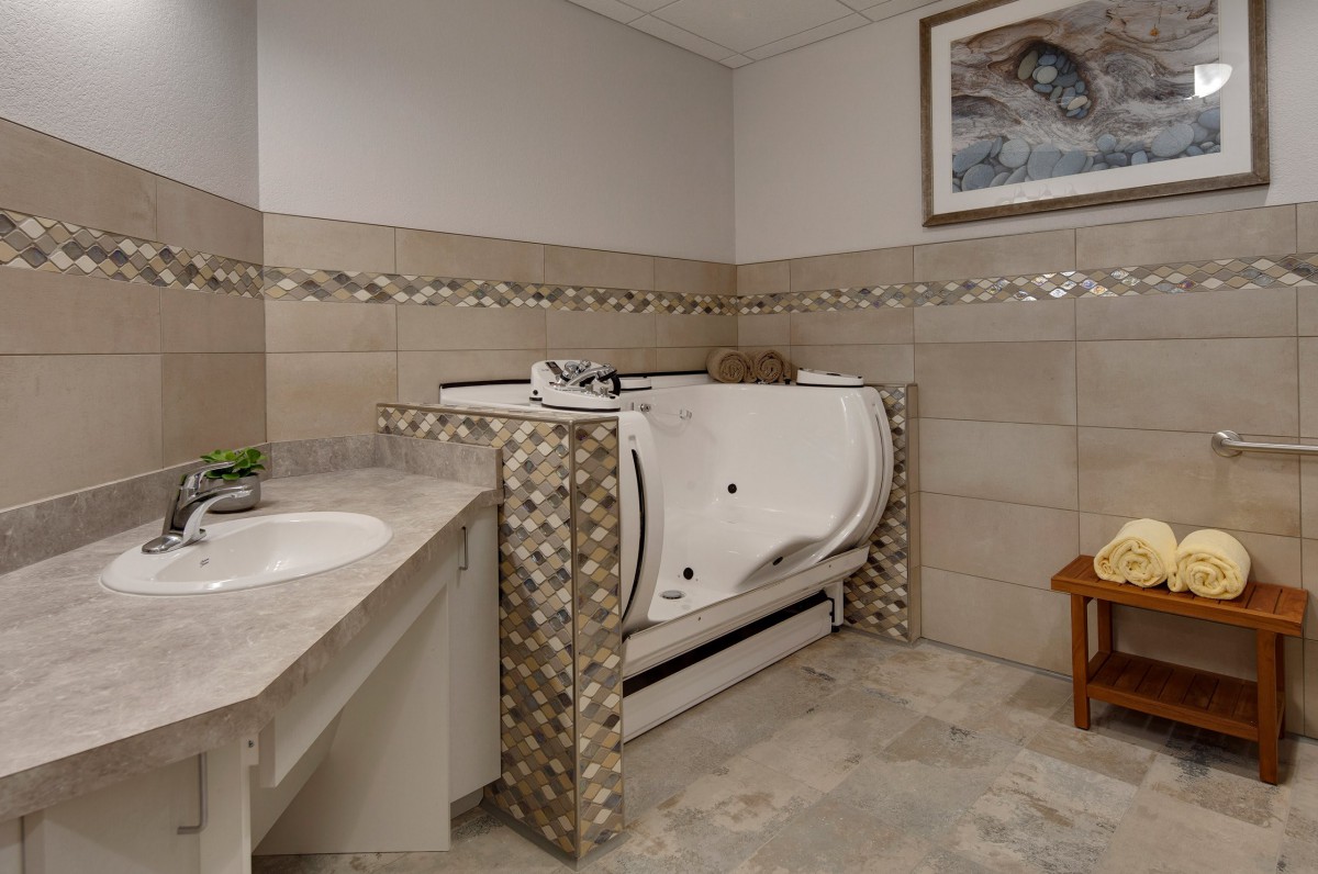 A well-designed bathroom featuring a walk-in tub with decorative tile work and a sink area.