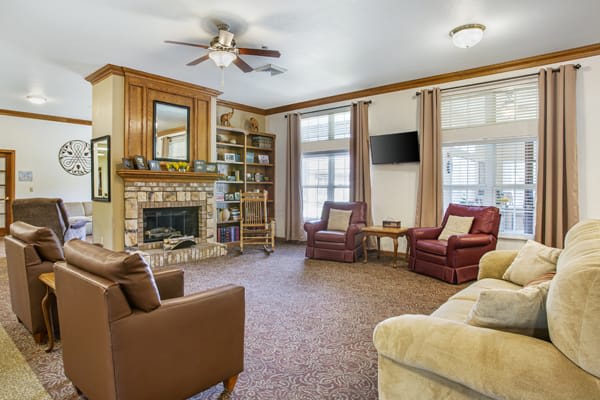 A cozy living room with a fireplace, comfortable seating, and a bookshelf.