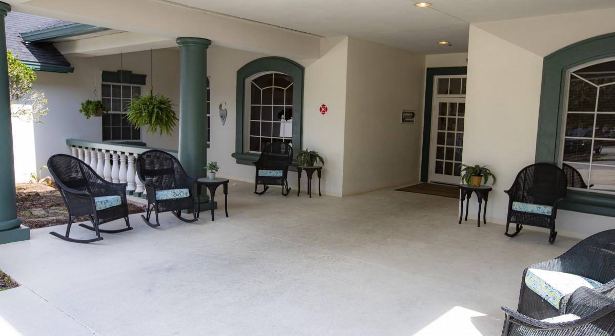 A covered entrance with seating and potted plants.