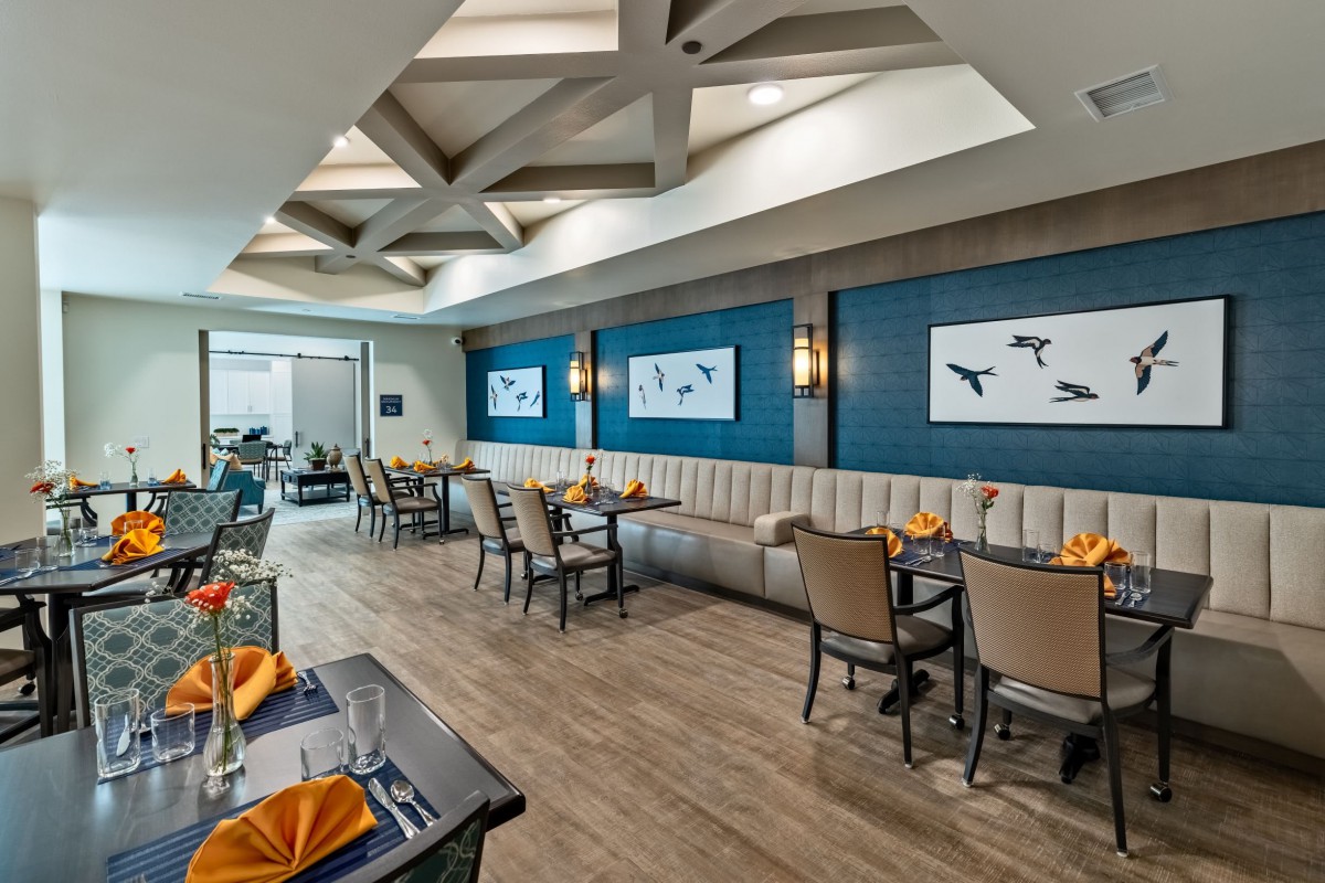 A modern restaurant interior featuring stylish tables and chairs, artwork on the walls, and elegant lighting.