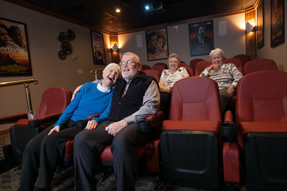Elderly couples enjoying a movie in a cozy theater setting.