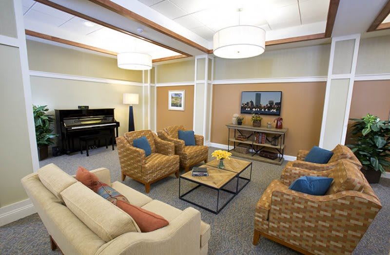 A cozy living room featuring comfortable seating, a piano, and modern decor.
