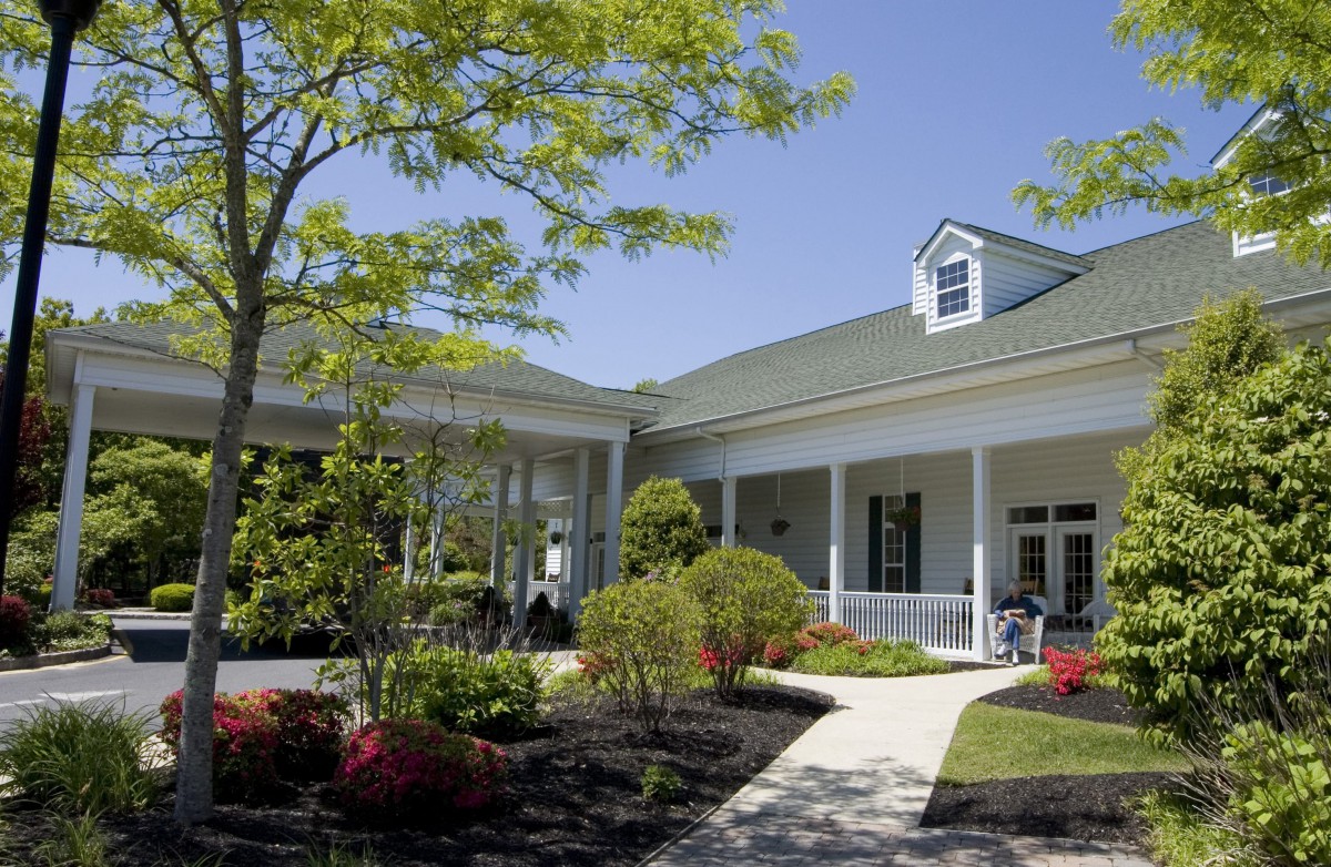 A picturesque view of a well-maintained building with a garden and pathway on a sunny day.