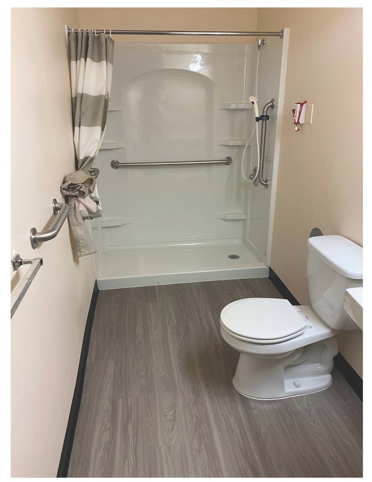 An accessible bathroom featuring a shower with grab bars and a toilet.