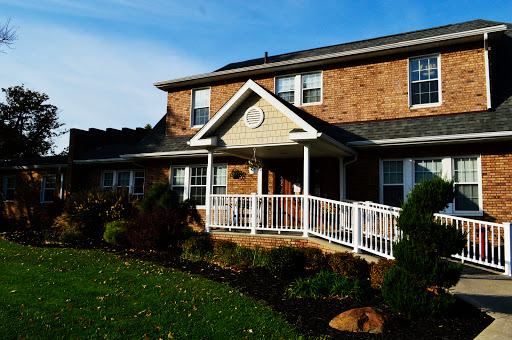 A cozy brick house featuring a welcoming front porch and well-maintained lawn.
