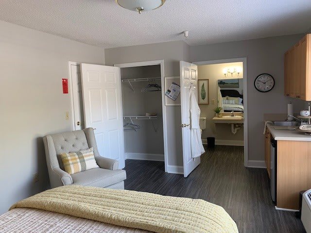 A cozy bedroom with a chair, bed, and view into the bathroom.