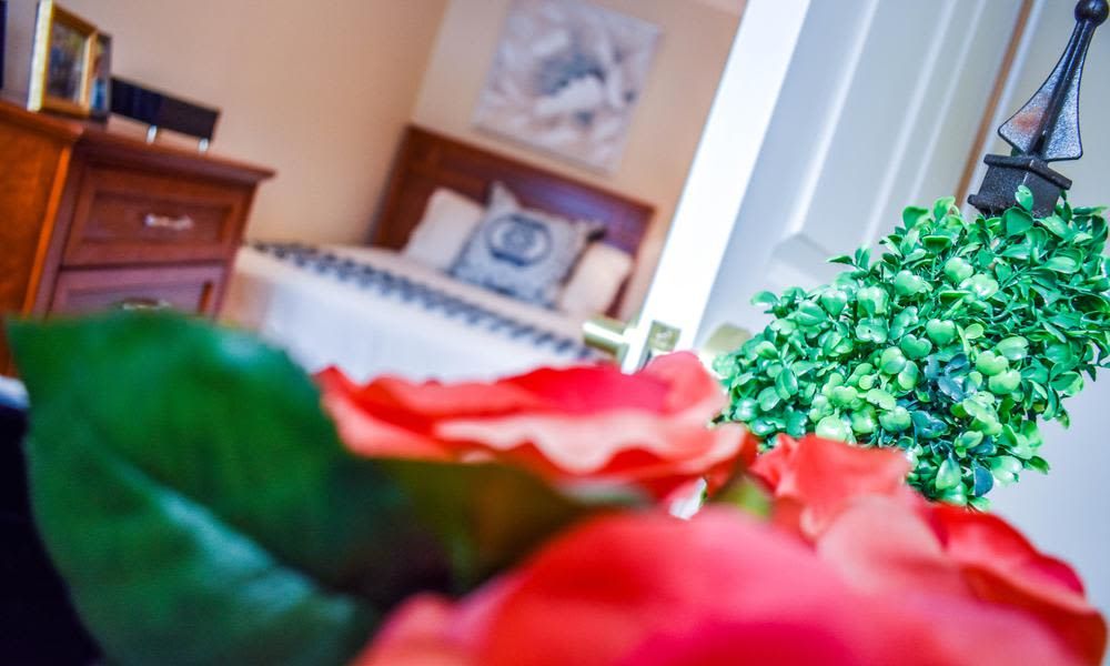 A cozy bedroom with a focus on vibrant red roses in the foreground.