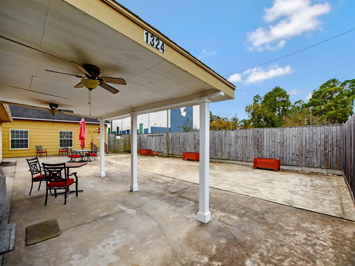 A spacious outdoor patio with a covered seating area and ceiling fan.
