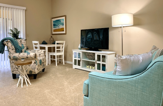 A cozy living room with a TV, sofa, and dining area.