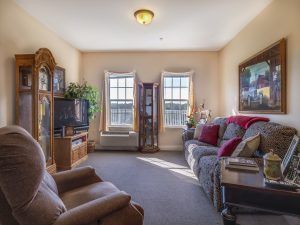A cozy living room with comfortable seating, a television, and artwork on the walls.