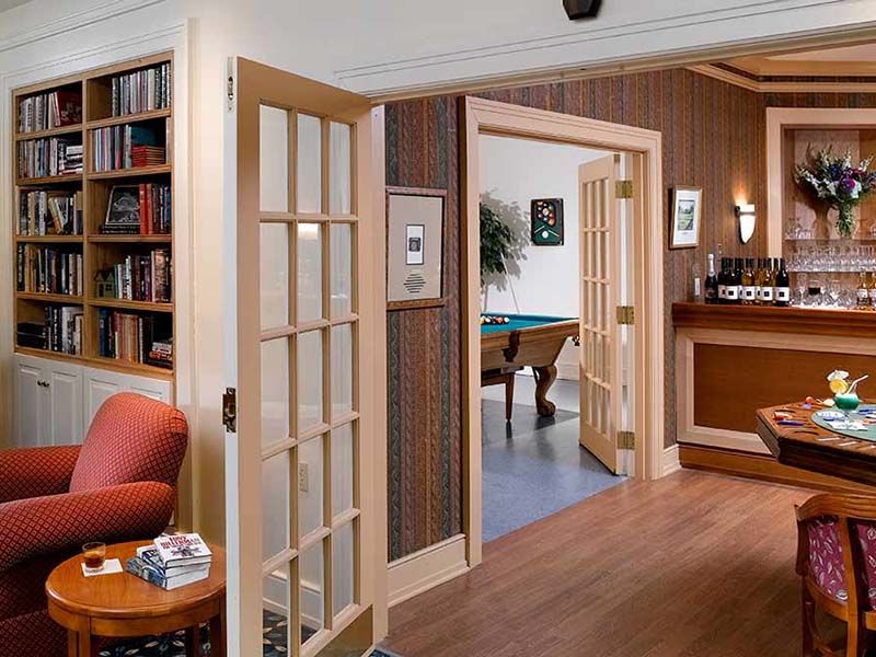 A cozy interior view featuring a living room with a library, French doors leading to a room with a pool table.
