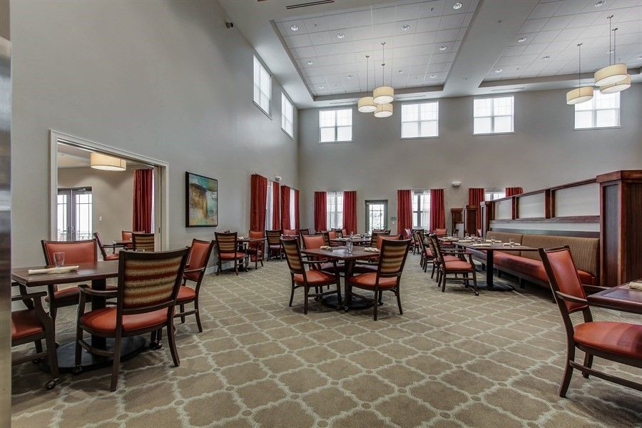 Spacious dining area with multiple tables, high ceilings, and large windows.