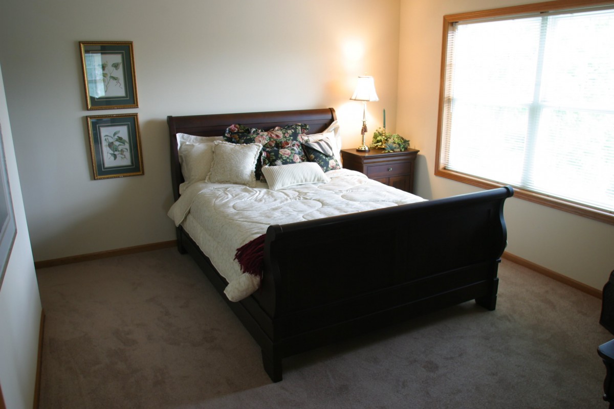A cozy bedroom with a large bed and a bedside lamp illuminating the space.