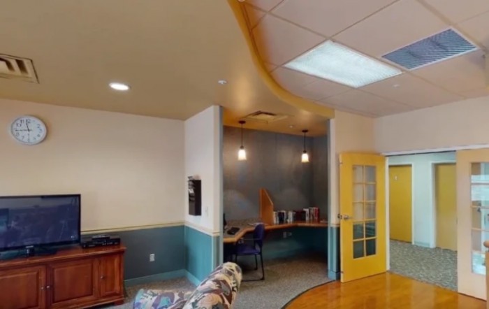 A modern office interior with a workspace, featuring colorful decor and lighting.