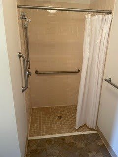 Accessible shower with grab bars and a curtain.