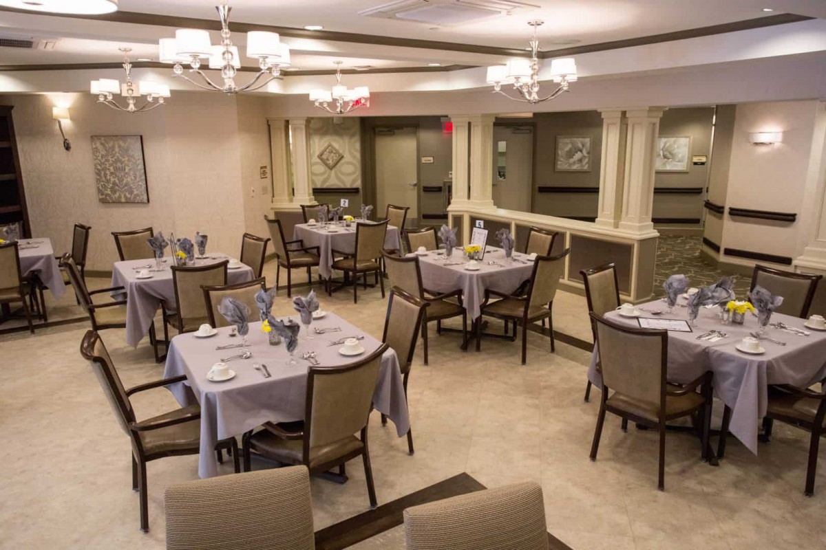 An elegant dining room setup with neatly arranged tables and chairs under chandeliers.